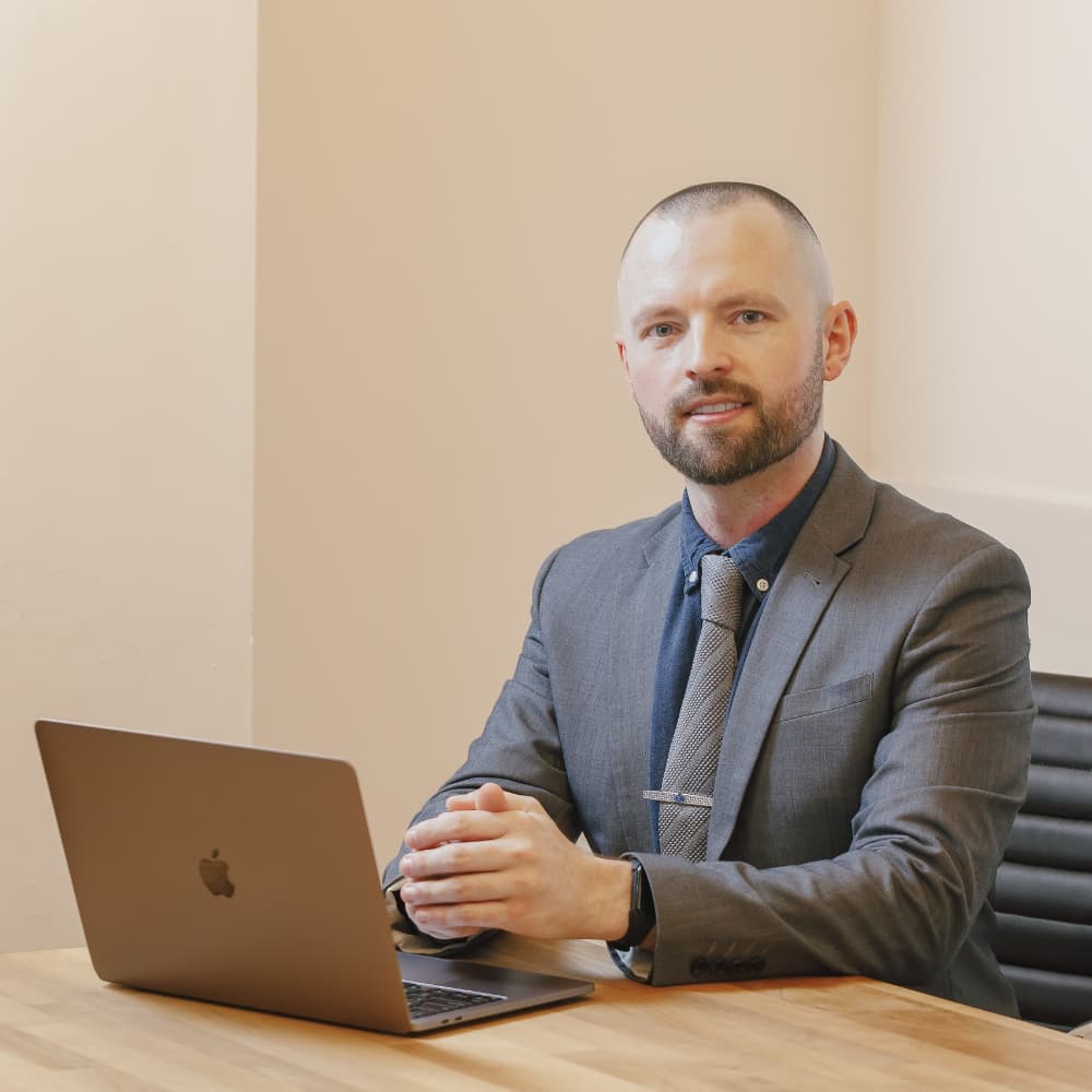 Dan Edwards in suit working at MacBook in office